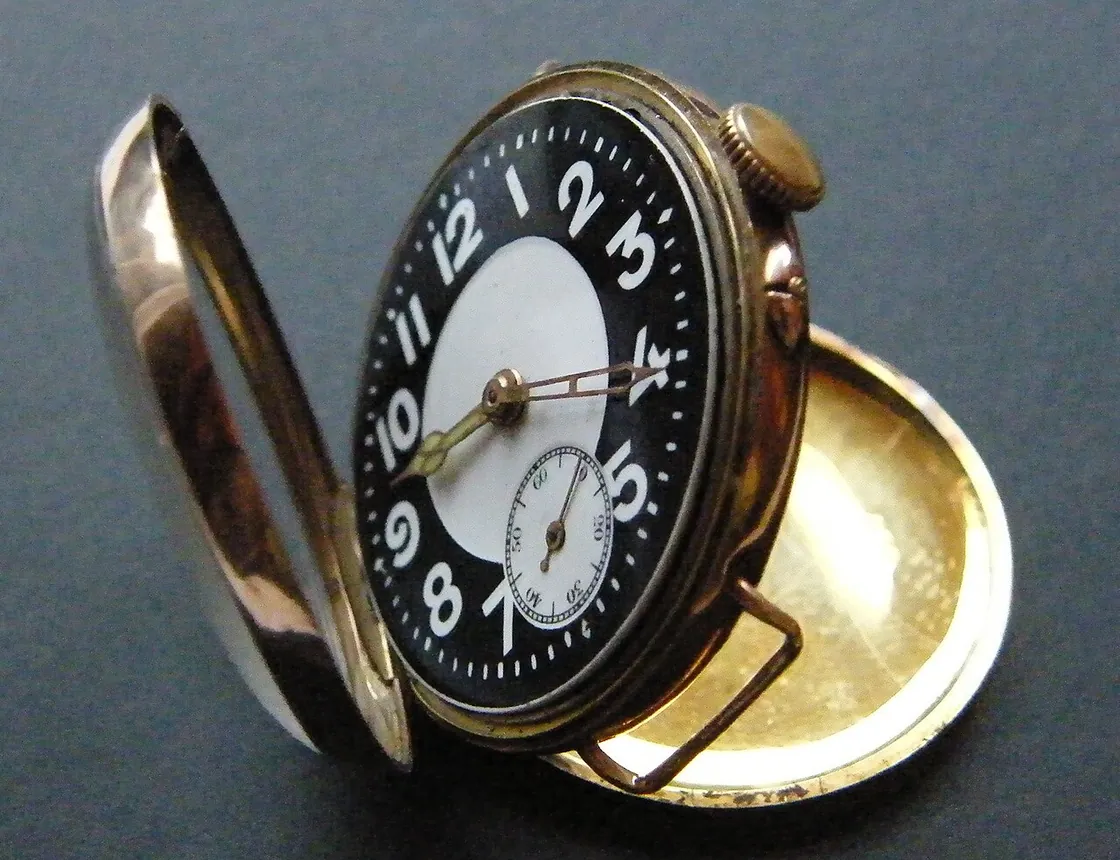 A complete gold trench-style wristwatch with white dial and black strap, a type worn by soldiers and aviators around World War I.